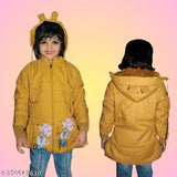 A young girl in a bright yellow hooded coat with a fluffy hood, standing outdoors