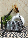 A box cross body bag with a camouflage pattern and an adjustable strap