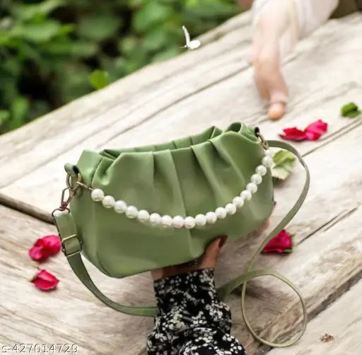 Green faux leather sling bag with pearl accents, adjustable strap