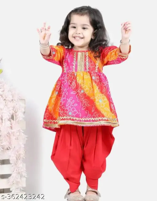 Red bandhej anarkali kurta set with dhoti pants, embellished with lace and bandhani work on cotton rayon. Indian party wear for girls aged 1-8 years
