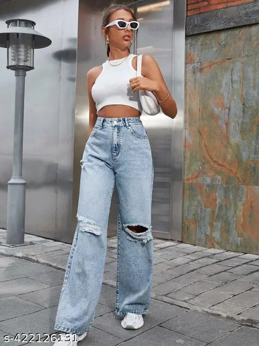 Woman in white tank top, wearing high-waisted bell-bottom jeans with rips and a small purse