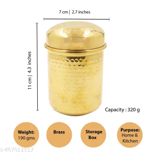 A brass canister with a lid, small in size, displayed against a scale