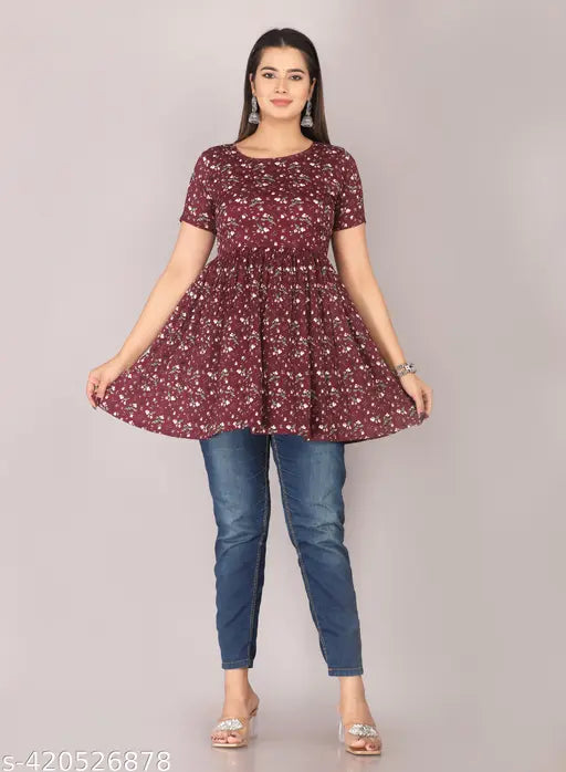 A woman in a maroon kurta with flared sleeves, standing against a grey background