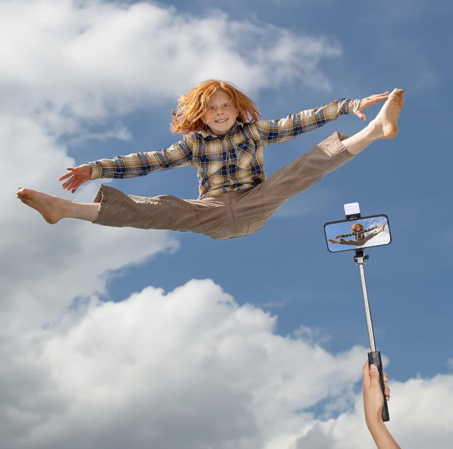 Black multi-functional selfie stick tripod with remote control, LED light, and adjustable phone holder