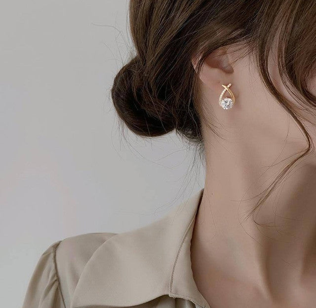 Gold plated brass stud earrings featuring a crossover twirl design, sold as a pair for women