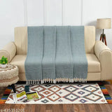 Cream couch with folded throw, patterned like a diamond weave, in shades of white, gray, and beige