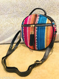 A small, colorful slingbag with faux leather trim and a canvas body