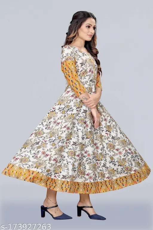 This is an image of a woman wearing a long, flared, colorful kurta with short sleeves and a patterned front panel. The kurta features a vibrant floral print and is adorned with what appears to be silver foil accents or embellishments on the bodice area