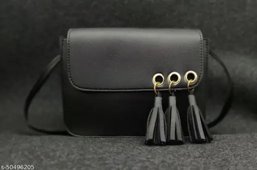 A black sling crossbody bag with tassel fringe details
