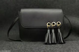 A black sling crossbody bag with tassel fringe details