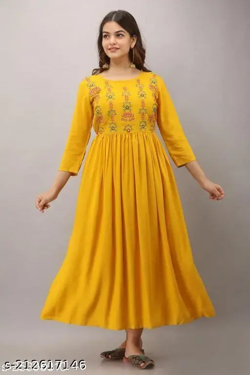 A woman in a vibrant yellow mustard Anarkali kurta with embroidered borders, standing against a white background