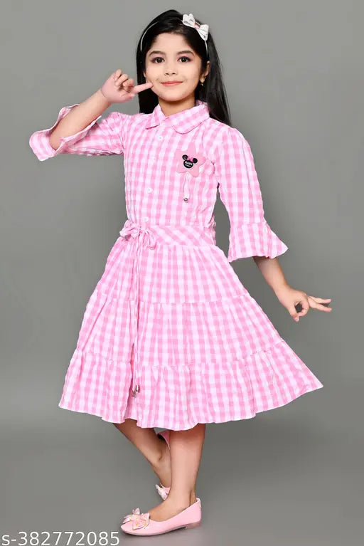 Pink checkered dress with ruffled sleeves and skirt, young girl pose