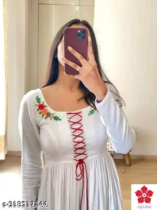 A white, long-sleeve dress with a lace trim and a red sash