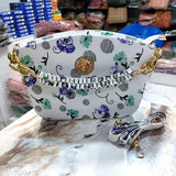 White bag with a colorful floral pattern, featuring a hand-knit handle