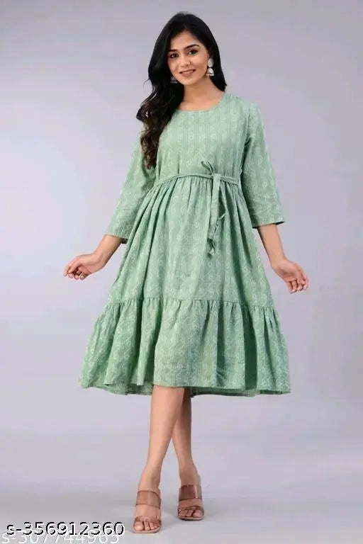 A woman in a green, sleeveless cotton tunic with a V-neck and flared skirt
