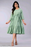 A woman in a green, sleeveless cotton tunic with a V-neck and flared skirt