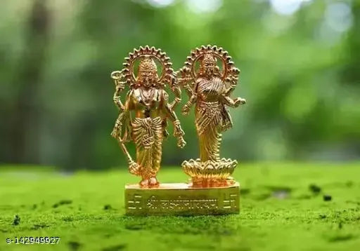 Gold-colored metal idol of Lord Laxmi and Lord Narayan, set against a natural backdrop