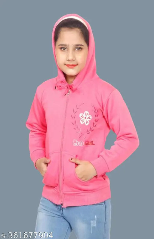 A girl wearing a pink jacket, standing in front of a blue wall