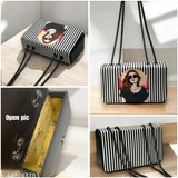 Black and white striped sling bag with cartoon face, open top