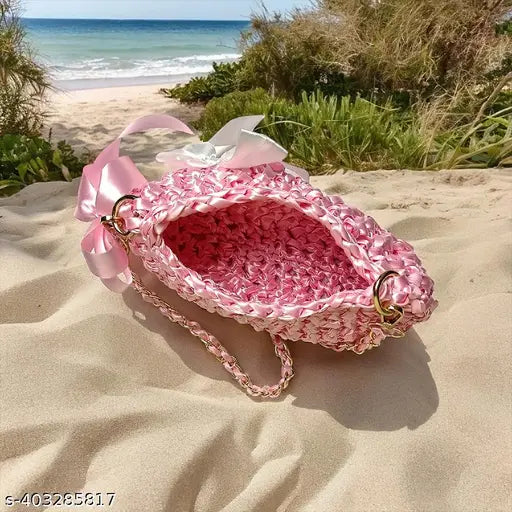 Handmade satin clutch with pink trim and golden metal accents, showcasing an exclusive and premium accessory on sandy beach