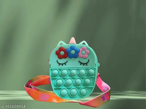 A green, plastic unicorn-themed fidget toy with a silky fabric texture and a zip closure inside a pink and orange ribbon bag, resembling a popper handbag with multiple card slots