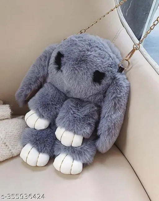 Furry gray stuffed animal with large eyes, wearing blue pants, sitting on a couch