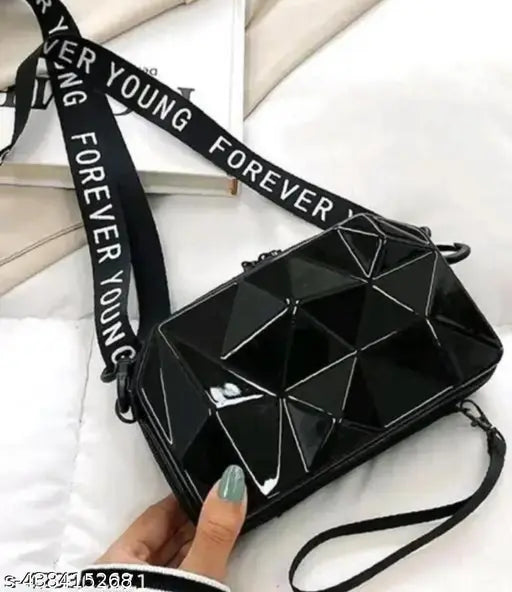 Black crossbody sling bag with 'Forever Young' written on strap, metallic studs and diamond shapes