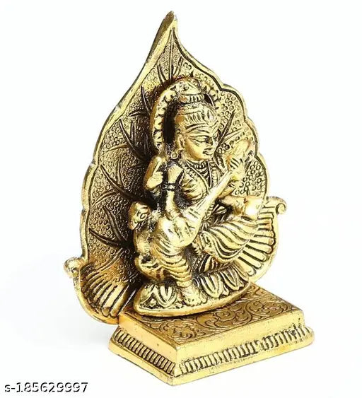 Golden antique metal statue of Maa Saraswati with a leaf backdrop
