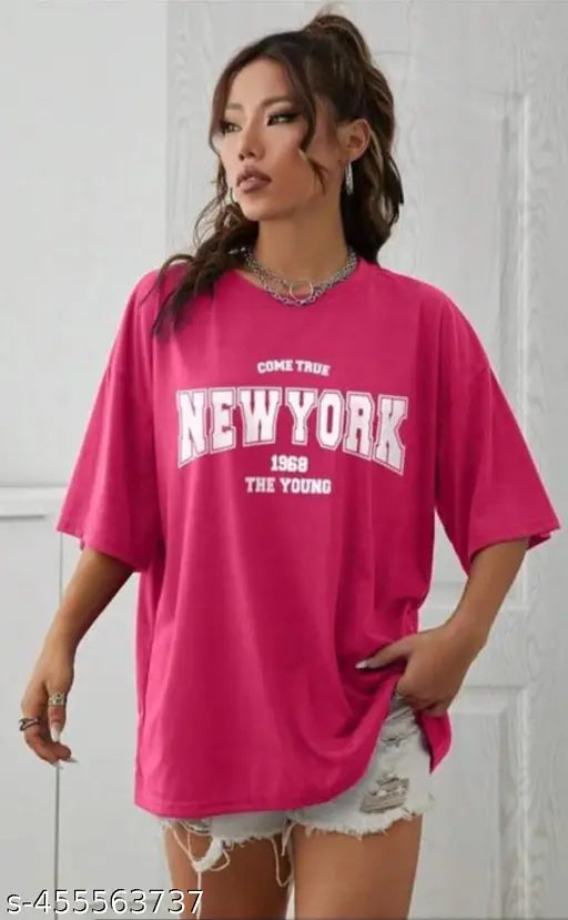 A person wearing a large pink t-shirt with white lettering