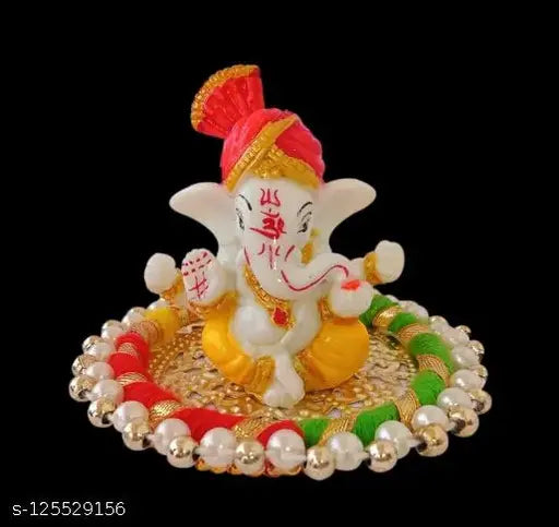 Handcrafted Lord Ganesha figurine on intricately decorated, white and gold plate with aasan background. Car decoration or home décor