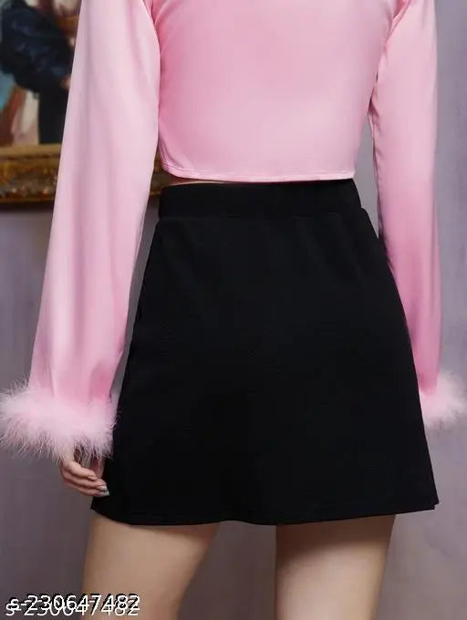A black top with a high neckline and flared sleeves, paired with a pink blouse and short skirt