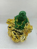 Laughing Buddha home decor figurine, green and gold, sitting on sofa