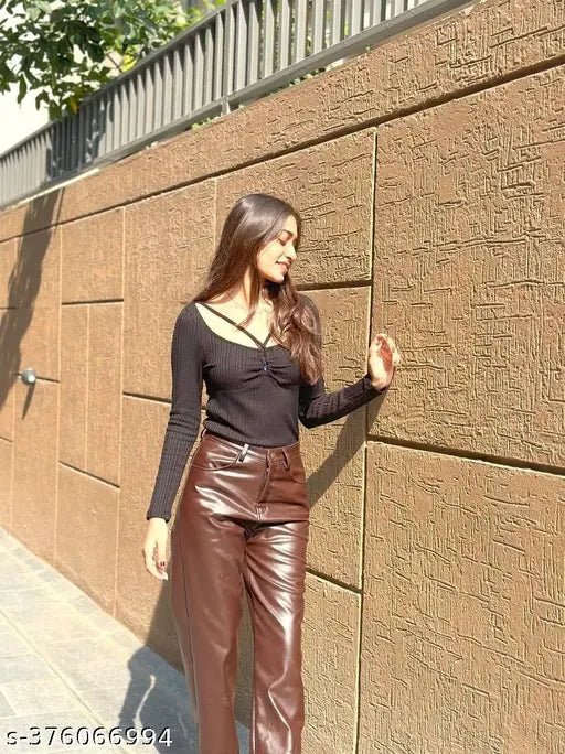 Brown leather trouser on a woman leaning against a brick wall