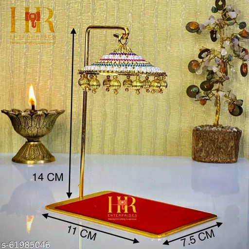 Copper-colored statue of Shivaji Maharaj, standing under an umbrella, with a candle base on a desk