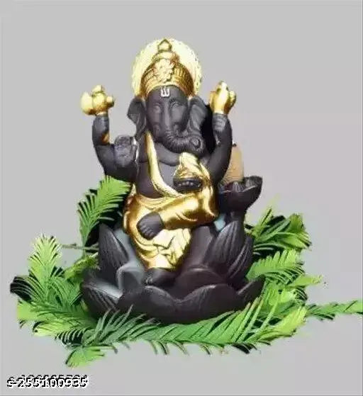 Black, gold, and silver metal religious figurine with backflow incense holder, set against natural greenery