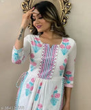 A woman wearing a white kurta and pants with paisley pattern, standing in front of a mirror