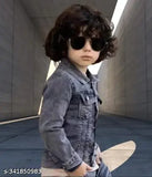 A young child wearing blue jeans, sunglasses, and standing against a minimalist backdrop