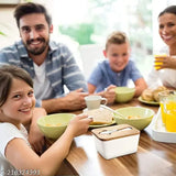 A large ceramic butter dish with a wooden lid, featuring a steel-bladed butter knife and a bamboo cover with a silicone sealing ring, set on a dining table with family members seated around it during mealtime