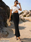Woman in a white top and black trousers with a woven clutch, standing on a rocky terrain