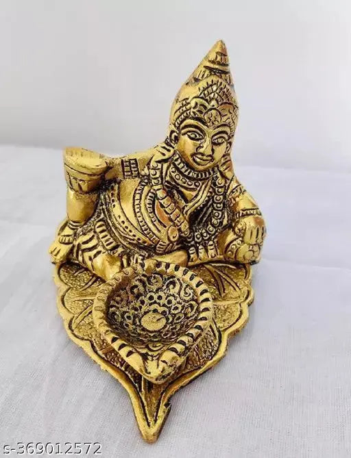 Golden metal showpiece of Kubera, Hindu deity of wealth and prosperity, sitting on lotus leaf with diya candle for good luck