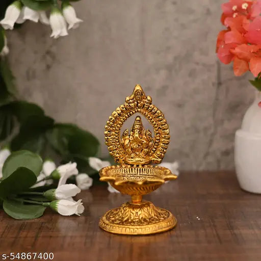 Gold idol of Lord Ganesha with a lit diya, traditional festival decoration