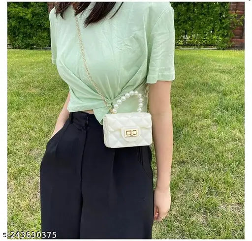 Silicone side shoulder crossbody sling bag for girls. Black straps, clear side pocket, gold hardware. Pearl embellished design