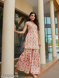 A woman posing in a traditional Indian outfit, possibly a lehenga or sari with intricate floral patterns, standing outdoors