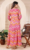 The image displays a long, full-length kurta with heavy gold foil print and embroidery. It is worn by a person standing next to an indoor setting with furniture