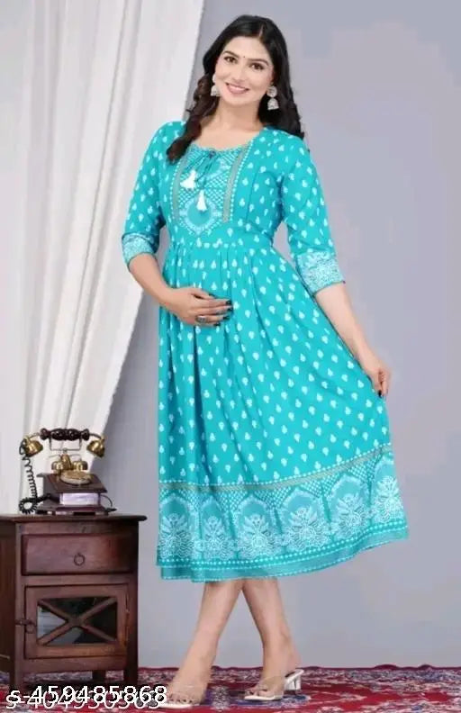 A woman wearing a long, blue, paisley patterned kameez standing against a white backdrop