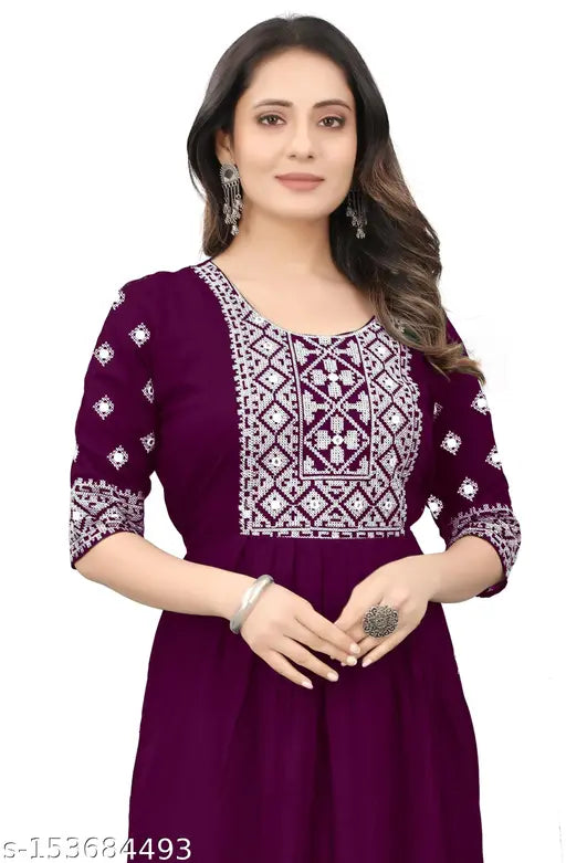 The image shows a woman wearing an embroidered purple kameez with a matching dupatta. She is posing against a plain background, and the kurti has long sleeves with detailed paisley embroidery throughout. It appears to be made of a lightweight fabric suitable for casual wear or occasions like weddings. The kurti is knee-length with a V-neckline and full sleeves, creating a flattering silhouette