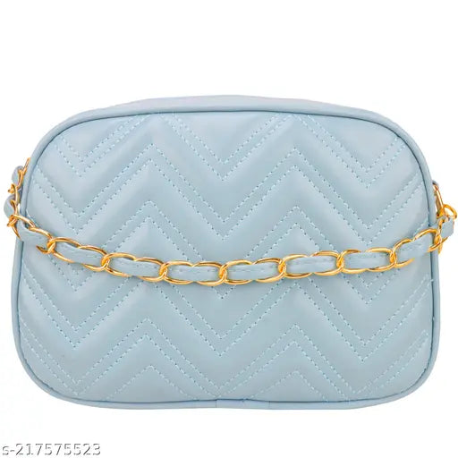 A light blue quilted slingbag with a cloud shape and a large, rectangular chain link strap