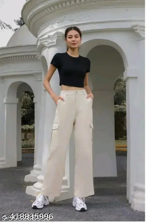 Woman wearing high-waisted, cropped beige trousers, black tank top, and white sneakers