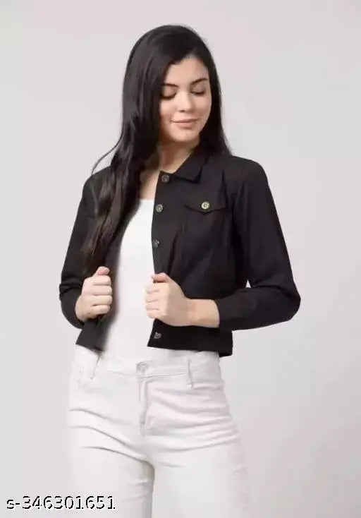 A woman wearing a black denim jacket with a dark shirt, white jeans, and her hair pulled back