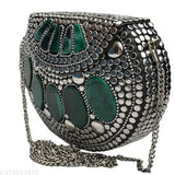 A silver metal hand clutch with green decorative stones